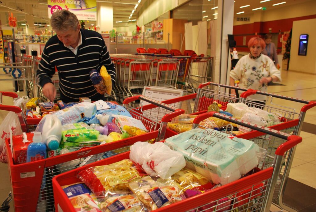 Organizator pregleduje zbrane donacije ob polnih vozičkih hrane na humanitarni akciji pred Mercatorjem.